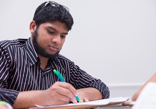 Pre-College Student taking notes inside a classroom