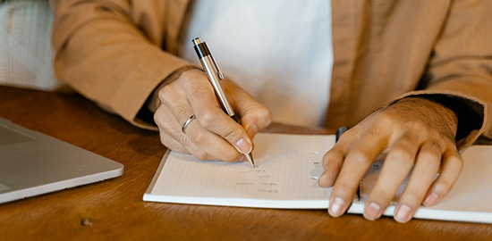 A pair of hands writing on a pad.